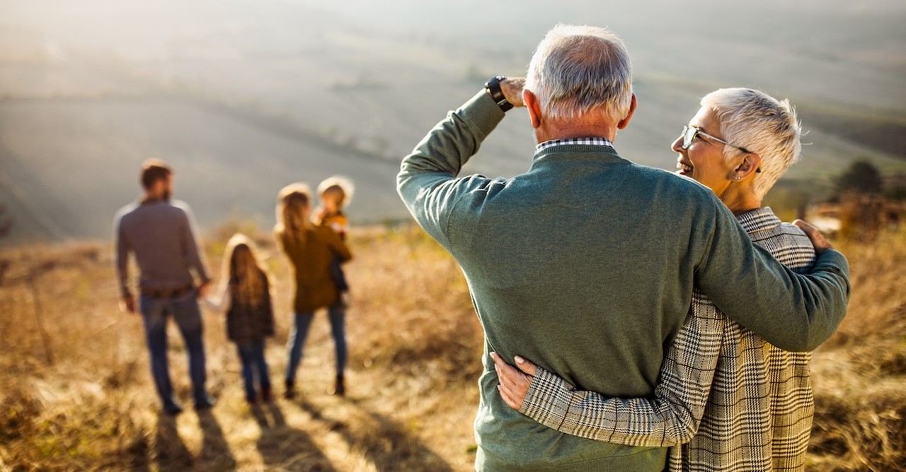 Proud grandparents senior couple watching family hiking on hill