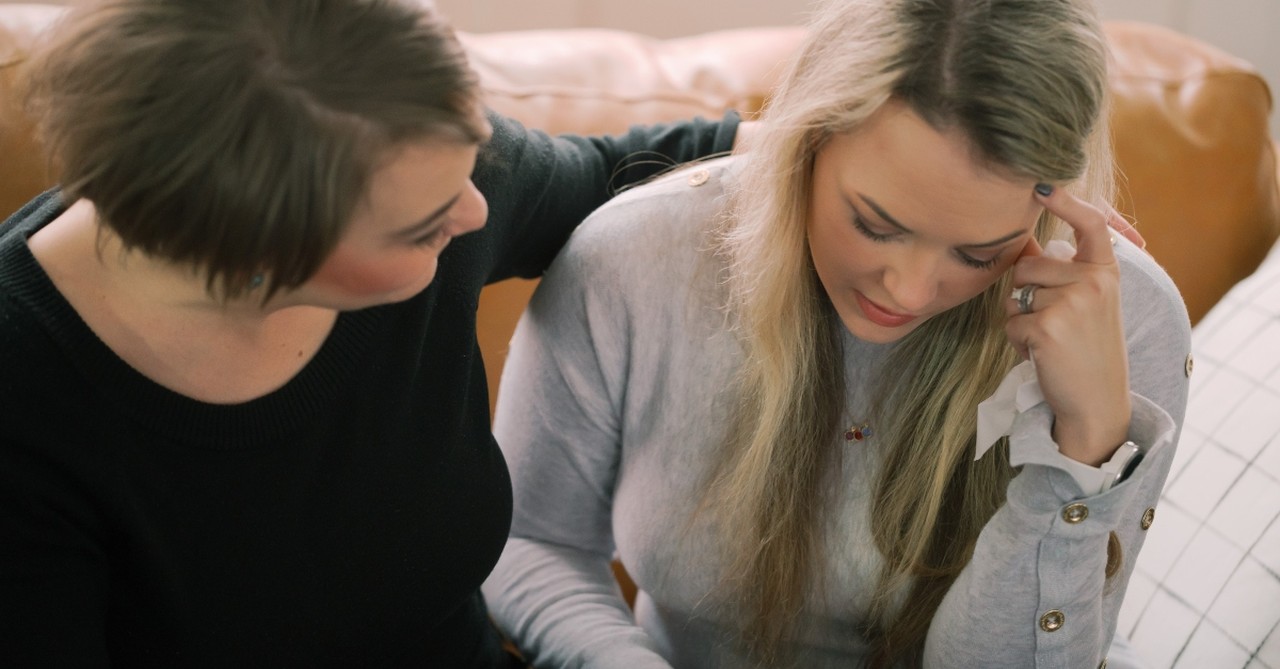 women friends comforting struggling arm over shoulder looking sad reading bible, healthcare sharing popular among christians